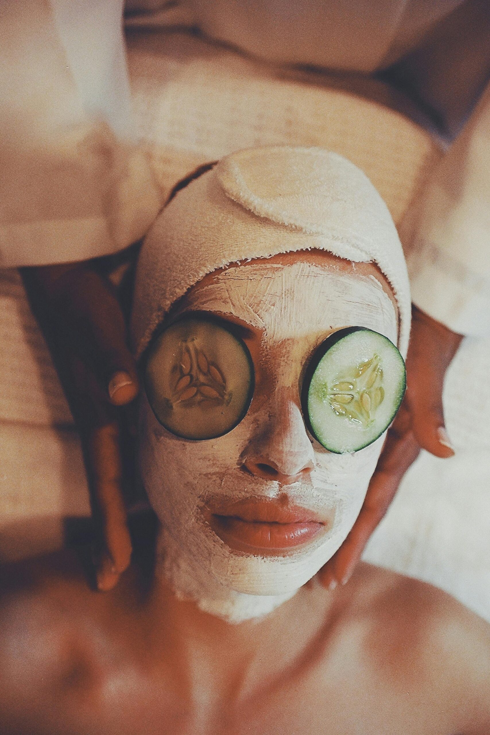 Close-up of a person receiving a facial spa treatment with a cucumber mask and gentle massage.